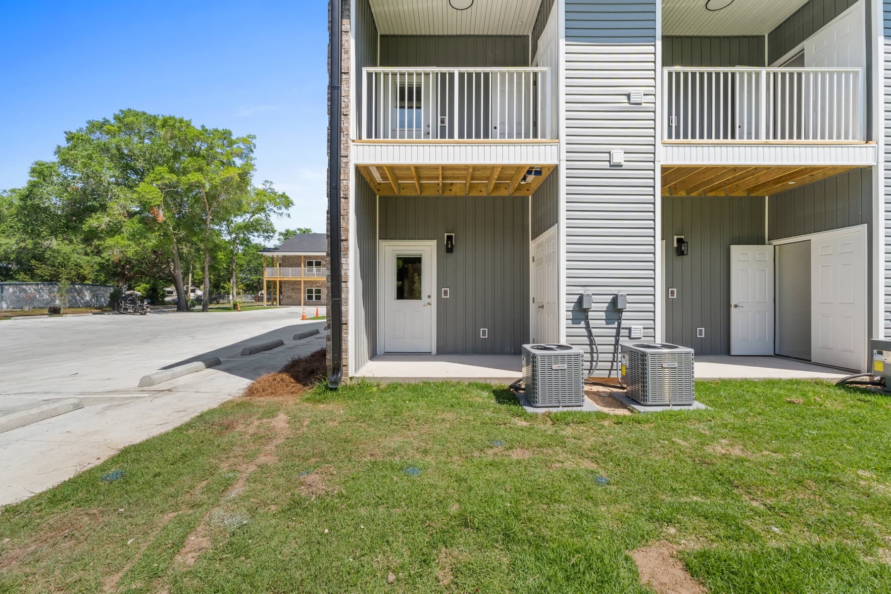 Rear elevation of a new multifamily building with board-and-batten siding, private balconies, and per-unit HVAC, built by Whitrock Associates in Northwest Florida