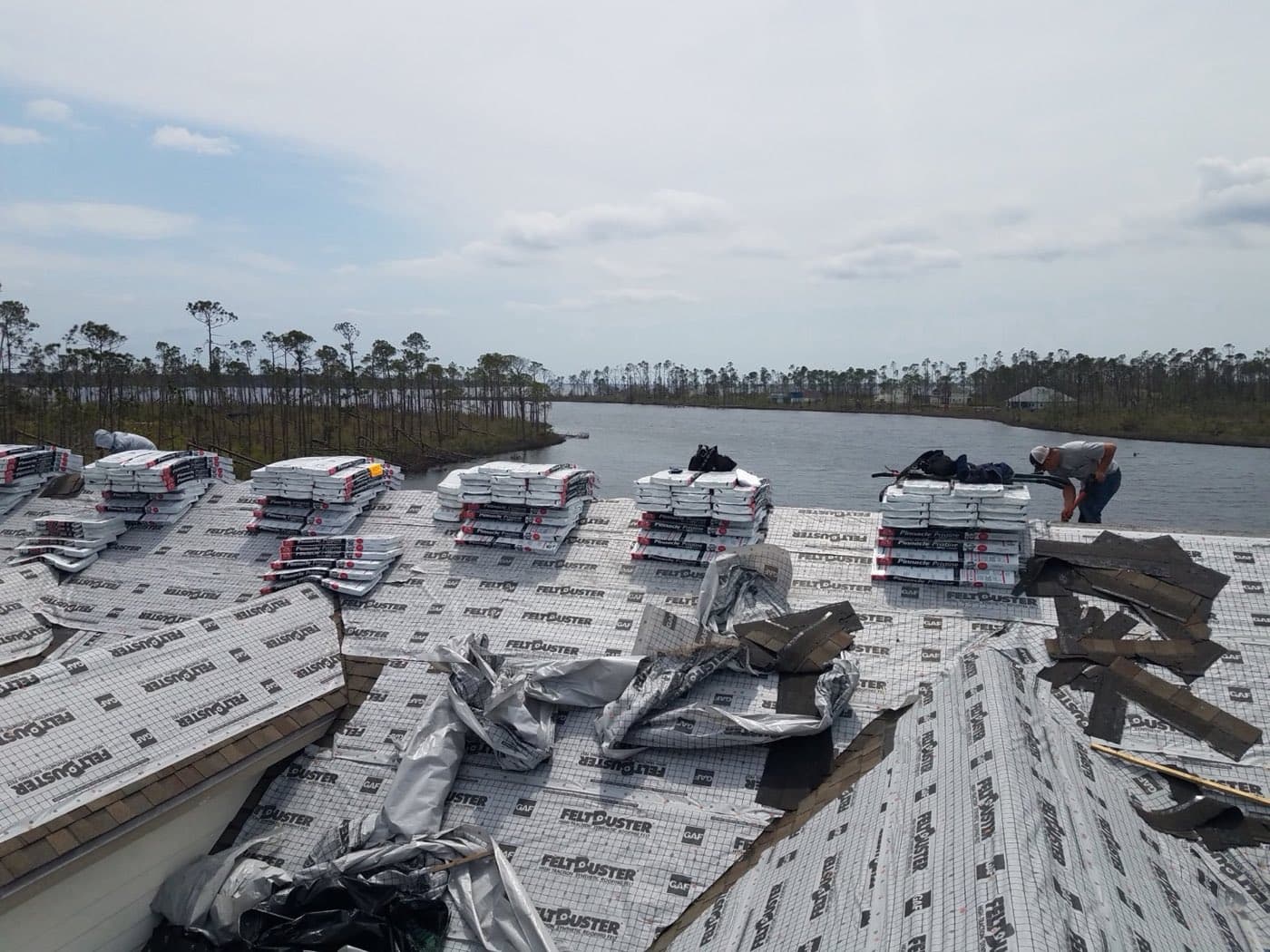 Shingle bundles staged for a post-storm reroof on a waterfront Northwest Florida home