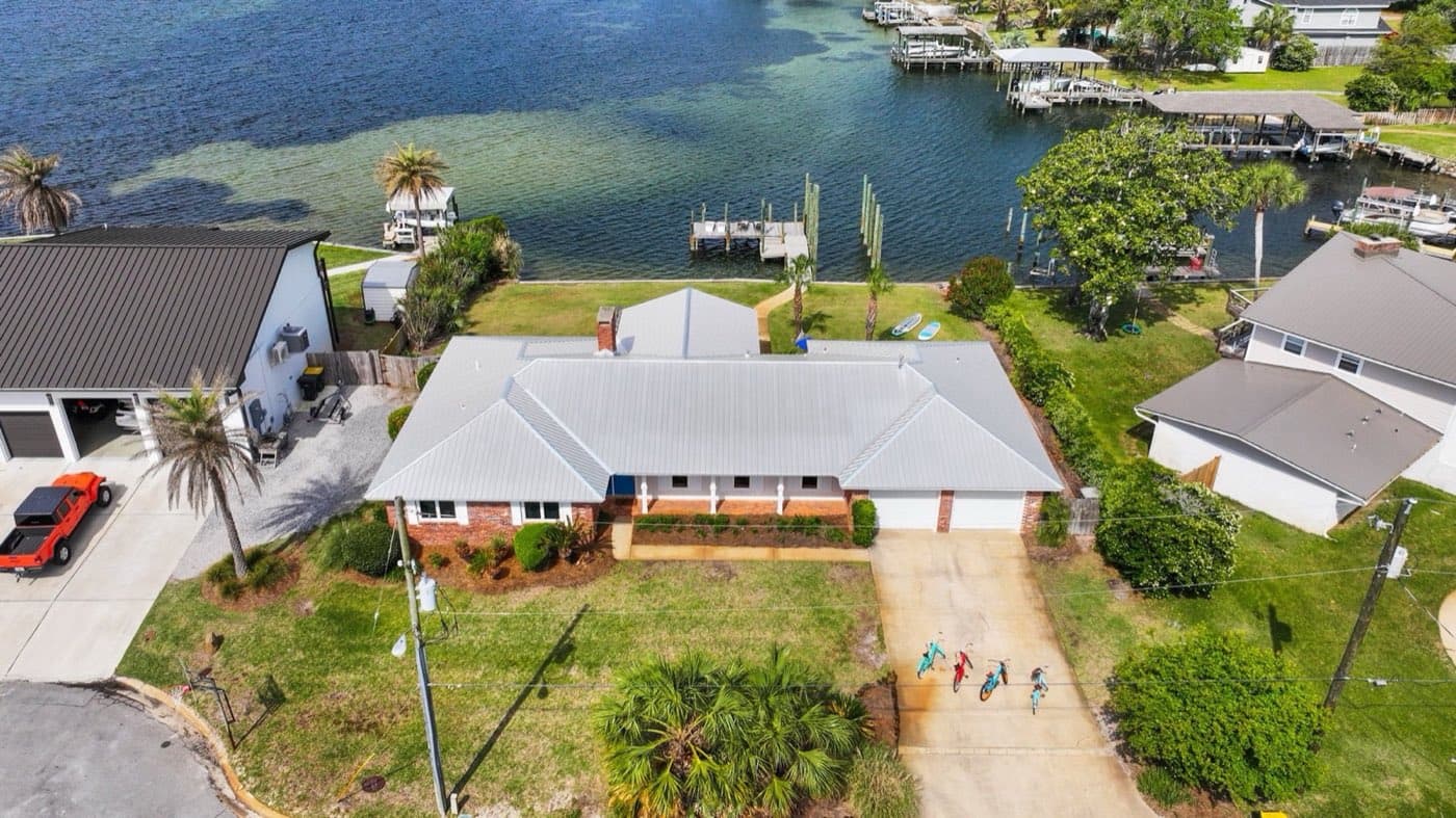 Aerial view of a waterfront Niceville, FL home after a full metal roof replacement by Whitrock Associates